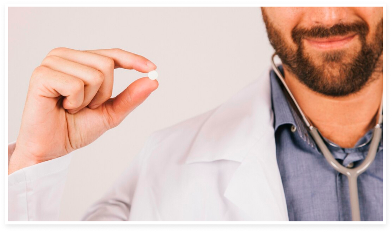 Doctor agarrando con los dedos una pastilla de finasterida